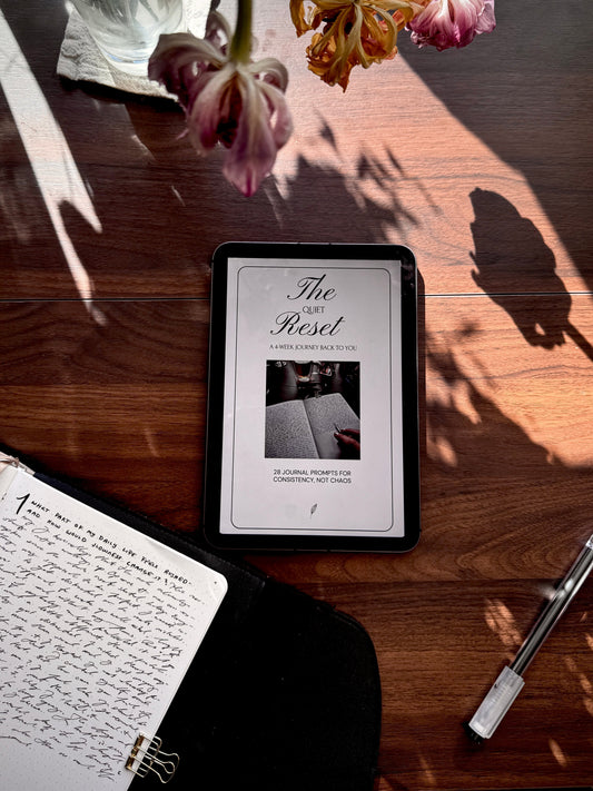 A cozy journaling scene with an iPad displaying ‘The Quiet Reset’ e-guide, surrounded by a handwritten journal, tulips, and soft natural light